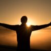 silhouette photo of man on cliff during sunset